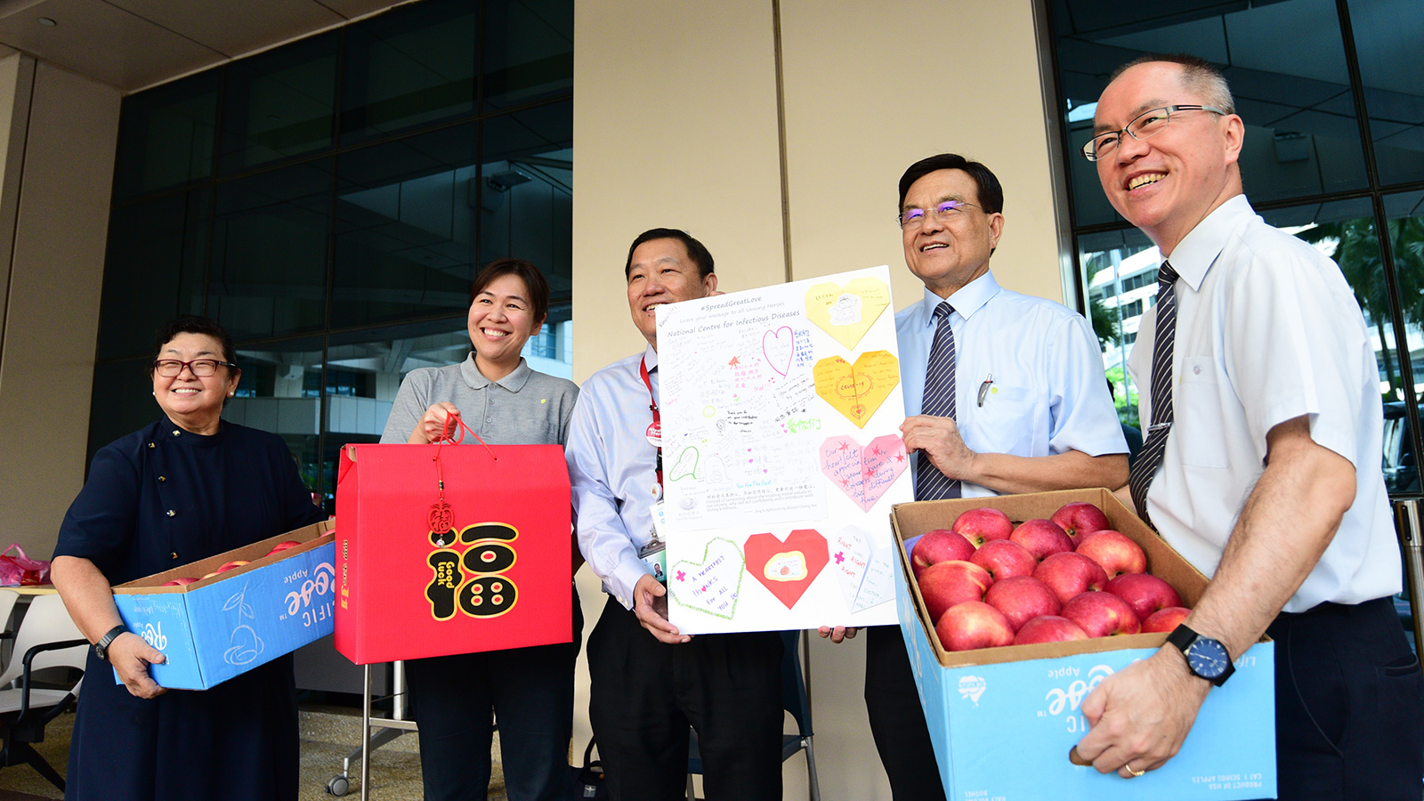 Tzu Chi CEO Mr Low Swee Seh (second from right) and volunteer representatives are handing over gift packs, apples and a large greeting card to Associate Professor Chin Jing Jih (middle), the Chairman of the Medical Board of Tan Tock Seng Hospital.