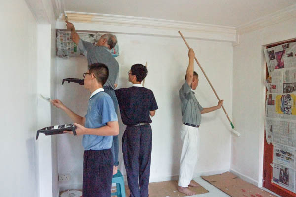 Five male volunteers help to paint the walls of Grandma Wong’s house after it was cleared of furniture while other volunteers busily sort out clutter in the kitchen and hall. Photo by Nichelle Chan