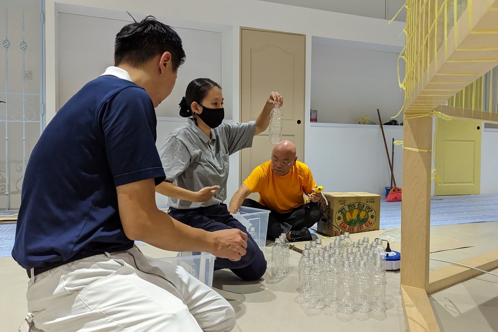 Volunteer Low Yanti (centre) conscientiously checking the plastic bottles meant for another installation. (Photo by Tey Inn Ping)